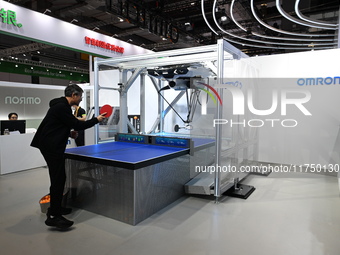 Visitors experience Omron's 9th generation table tennis coaching robot at the Technical equipment exhibition area of the 7th China Internati...