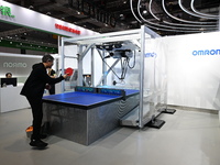 Visitors experience Omron's 9th generation table tennis coaching robot at the Technical equipment exhibition area of the 7th China Internati...