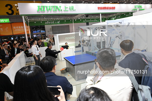 Visitors experience Omron's 9th generation table tennis coaching robot at the Technical equipment exhibition area of the 7th China Internati...