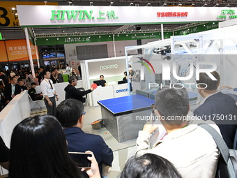 Visitors experience Omron's 9th generation table tennis coaching robot at the Technical equipment exhibition area of the 7th China Internati...