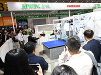 Visitors experience Omron's 9th generation table tennis coaching robot at the Technical equipment exhibition area of the 7th China Internati...