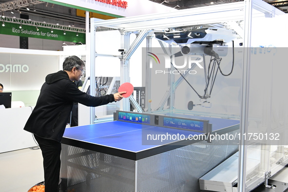 Visitors experience Omron's 9th generation table tennis coaching robot at the Technical equipment exhibition area of the 7th China Internati...