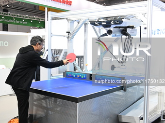 Visitors experience Omron's 9th generation table tennis coaching robot at the Technical equipment exhibition area of the 7th China Internati...