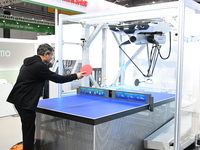 Visitors experience Omron's 9th generation table tennis coaching robot at the Technical equipment exhibition area of the 7th China Internati...