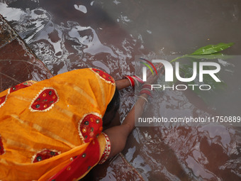 A Hindu devotee lies on the banks of the river Ganges as she offers prayers to the Sun god during the religious festival of Chhat Puja in Ko...