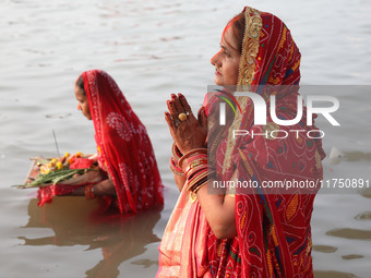 Hindu devotees stand in the waters of the river Ganges to offer prayers to the Sun god during the Hindu religious festival of Chhat Puja in...