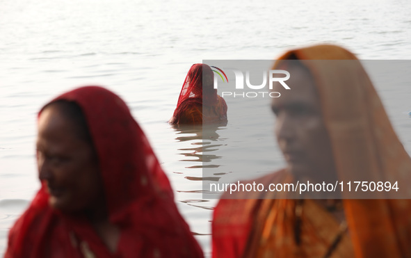 Hindu devotees stand in the waters of the river Ganges to offer prayers to the Sun god during the Hindu religious festival of Chhat Puja in...