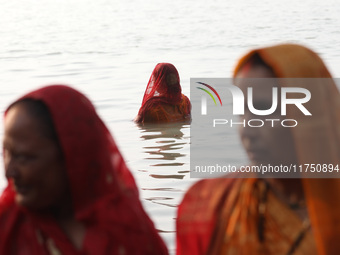 Hindu devotees stand in the waters of the river Ganges to offer prayers to the Sun god during the Hindu religious festival of Chhat Puja in...