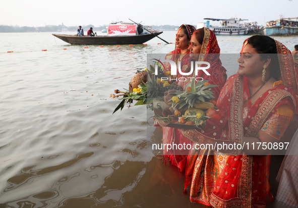 Hindu devotees hold offerings as they stand in the waters of the river Ganges to offer prayers to the Sun god during the Hindu religious fes...