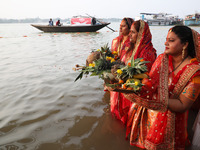 Hindu devotees hold offerings as they stand in the waters of the river Ganges to offer prayers to the Sun god during the Hindu religious fes...