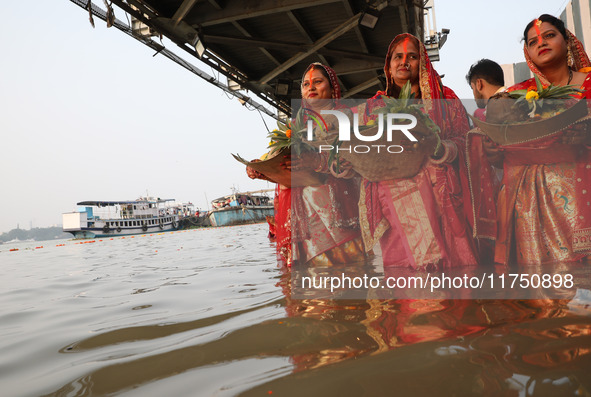 Hindu devotees hold offerings as they stand in the waters of the river Ganges to offer prayers to the Sun god during the Hindu religious fes...