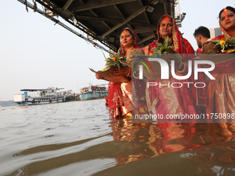 Hindu devotees hold offerings as they stand in the waters of the river Ganges to offer prayers to the Sun god during the Hindu religious fes...