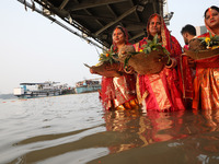 Hindu devotees hold offerings as they stand in the waters of the river Ganges to offer prayers to the Sun god during the Hindu religious fes...