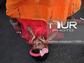 A Hindu woman steps over a child in a ritual seeking blessings for the child from the Sun god during the religious festival of Chhat Puja in...