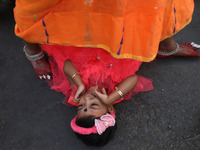 A Hindu woman steps over a child in a ritual seeking blessings for the child from the Sun god during the religious festival of Chhat Puja in...