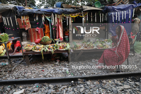 A Hindu devotee sits beside railway tracks in front of her hut as she worships the Sun god on the banks of the river Ganges during the relig...