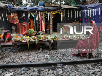 A Hindu devotee sits beside railway tracks in front of her hut as she worships the Sun god on the banks of the river Ganges during the relig...