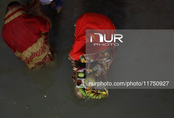 Hindu devotees hold offerings as they worship the Sun god on the banks of the river Ganges during the religious festival of Chhat Puja in Ko...