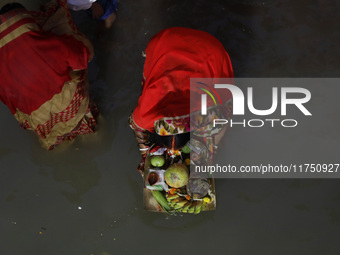 Hindu devotees hold offerings as they worship the Sun god on the banks of the river Ganges during the religious festival of Chhat Puja in Ko...