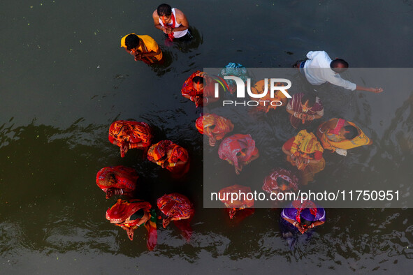 Female devotees offer prayers to the Sun god at a riverside 70 kilometers outside of Kolkata, India, on November 7, 2024, during the Chhath...