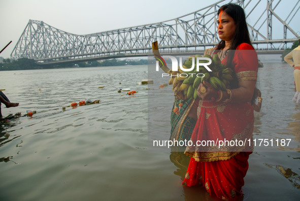 Hindu women devotees perform rituals in a water body of the river Ganga in front of the iconic Howrah Bridge during the Hindu festival Chhat...