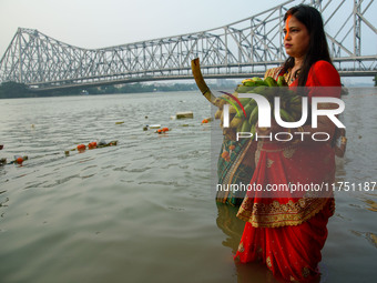 Hindu women devotees perform rituals in a water body of the river Ganga in front of the iconic Howrah Bridge during the Hindu festival Chhat...