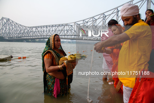 Hindu women devotees perform rituals in the river Ganga in front of the iconic Howrah Bridge during the Hindu festival Chhath in Kolkata, In...