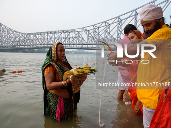 Hindu women devotees perform rituals in the river Ganga in front of the iconic Howrah Bridge during the Hindu festival Chhath in Kolkata, In...