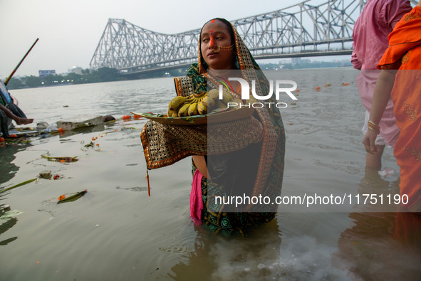 Hindu women devotees perform rituals in a water body of the river Ganga in front of the iconic Howrah Bridge during the Hindu festival Chhat...