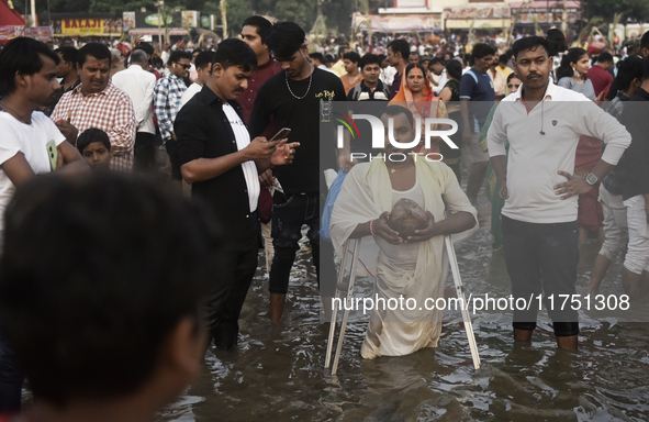 A Hindu devotee with an elbow crutch performs religious rituals near the Arabian Sea on the day of the Chhath Puja festival in Mumbai, India...