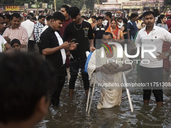 A Hindu devotee with an elbow crutch performs religious rituals near the Arabian Sea on the day of the Chhath Puja festival in Mumbai, India...