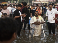 A Hindu devotee with an elbow crutch performs religious rituals near the Arabian Sea on the day of the Chhath Puja festival in Mumbai, India...