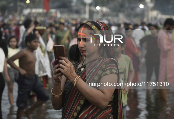 A Hindu devotee takes a mobile photo of religious rituals near the Arabian Sea during the Chhath Puja festival in Mumbai, India, on November...