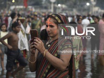 A Hindu devotee takes a mobile photo of religious rituals near the Arabian Sea during the Chhath Puja festival in Mumbai, India, on November...