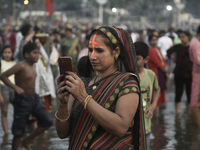 A Hindu devotee takes a mobile photo of religious rituals near the Arabian Sea during the Chhath Puja festival in Mumbai, India, on November...