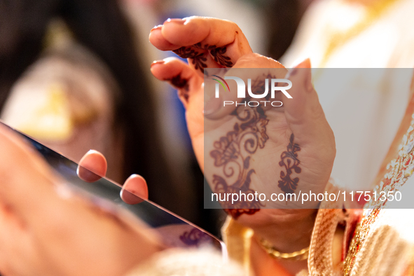 A bedouin bride dressed in traditional bedouin dress and henna hand tattoo uses mobile phone as she celebrates her wedding together with her...