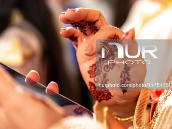 A bedouin bride dressed in traditional bedouin dress and henna hand tattoo uses mobile phone as she celebrates her wedding together with her...