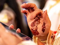 A bedouin bride dressed in traditional bedouin dress and henna hand tattoo uses mobile phone as she celebrates her wedding together with her...