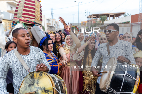 Bedouin wedding guests  dressed in traditional bedouin dresses and head covers dance and sing on the street as they escort the bride to her...