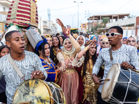 Bedouin wedding guests  dressed in traditional bedouin dresses and head covers dance and sing on the street as they escort the bride to her...