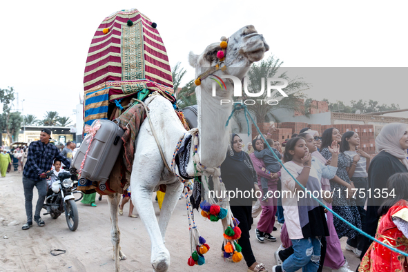 Bedouin wedding guests  dressed in traditional bedouin dresses and head covers dance and sing on the street as they escort the bride to her...