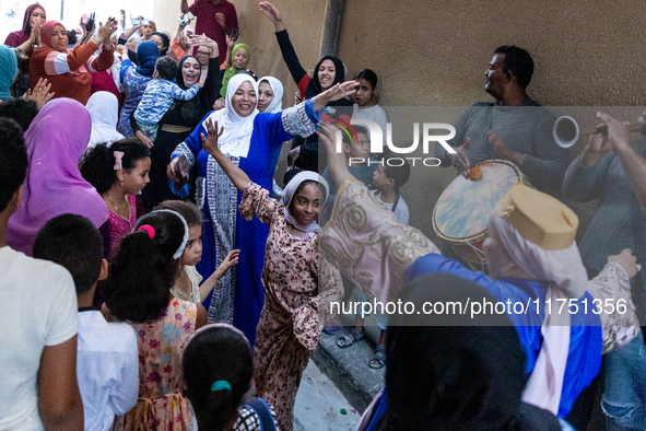 Bedouin wedding guests  dressed in traditional bedouin dresses and head covers dance and sing on the street as they escort the bride to her...