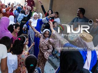 Bedouin wedding guests  dressed in traditional bedouin dresses and head covers dance and sing on the street as they escort the bride to her...