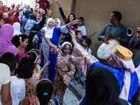 Bedouin wedding guests  dressed in traditional bedouin dresses and head covers dance and sing on the street as they escort the bride to her...