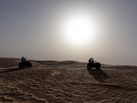 Tourists ride on quad bikes on dunes of Eastern Sahara desert on a sunny day on October 30, 2024 near Douz, Tunisia. (