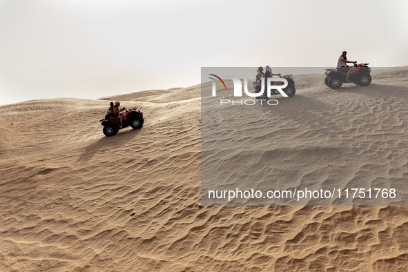 Tourists ride on quad bikes on dunes of Eastern Sahara desert on a sunny day on October 30, 2024 near Douz, Tunisia. 