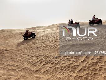 Tourists ride on quad bikes on dunes of Eastern Sahara desert on a sunny day on October 30, 2024 near Douz, Tunisia. (