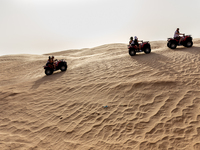 Tourists ride on quad bikes on dunes of Eastern Sahara desert on a sunny day on October 30, 2024 near Douz, Tunisia. (