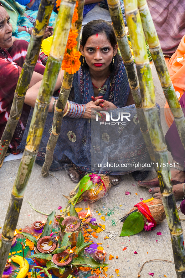 Hindu devotees perform rituals and offer prayers at sunset on the banks of the River Sabarmati during the Chhath Puja festival in Ahmedabad,...