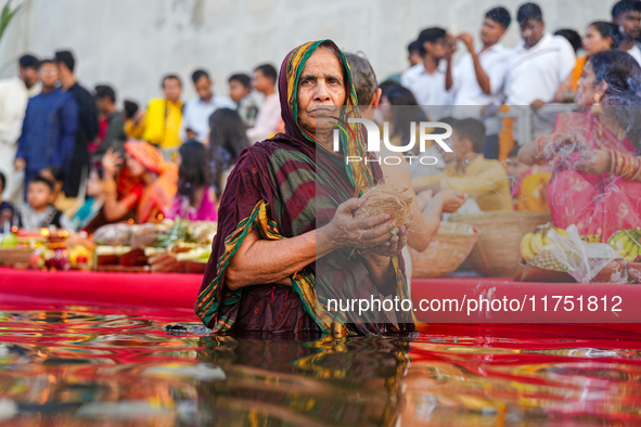 Hindu devotees perform rituals and offer prayers at sunset on the banks of the River Sabarmati during the Chhath Puja festival in Ahmedabad,...